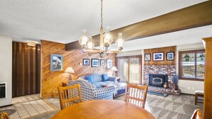 Ein gemütliches Wohnzimmer mit einer Holzwand, einem Kamin und einem Essbereich mit Holztisch und -stühlen.