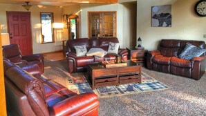 A cozy living room with leather sofas, a coffee table, and a rug. - Bear Paw Ranch Vacation Rentals (Bigfork)