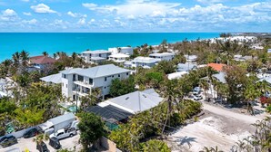 A coastal residential area with modern houses, a clear blue sky, and a view of the ocean. - SERENITY - Luxury Captiva Home, 4 Homes From the Beach (Captiva)