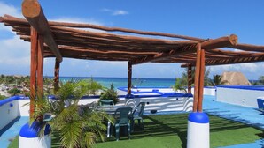 Ein überdachter Außenbereich mit Pool, Liegestühlen und Blick auf den Ozean.