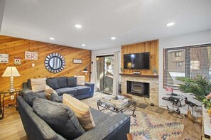 Ein modernes Wohnzimmer mit Kamin, Fernseher und Sofa.