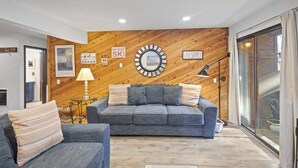 Uma sala de estar moderna com parede de madeira, um sofá, uma mesa de centro e uma luminária.