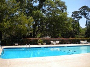 Relax by the pool surrounded by lush greenery and comfortable lounge chairs.