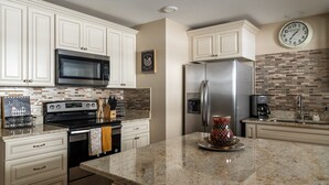 A modern kitchen with white cabinets, stainless steel appliances, a granite countertop, and a clock on the wall. - The Last Best Place With Mountain Views (Bozeman)