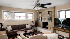 A living room with a brown leather sofa, beige armchairs, a coffee table, and a fireplace. - The Last Best Place With Mountain Views (Bozeman)