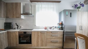 Une cuisine moderne avec des meubles en bois, un réfrigérateur en acier inoxydable et un four encastré.