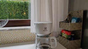 Une machine à café posée sur un comptoir près d’une fenêtre donnant sur un paysage verdoyant.