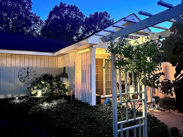 A house with a clock on the wall, a covered porch, and a garden.