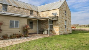 A stone farmhouse with a metal roof, a satellite dish, and a covered porch.