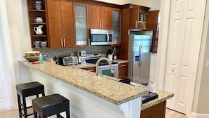 Cocina con encimeras de granito, electrodomésticos de acero inoxidable y armarios de madera.