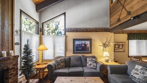 Ein gemütliches Wohnzimmer mit Kamin, zwei Sofas, einem Couchtisch und einem kleinen Beistelltisch mit Lampen.