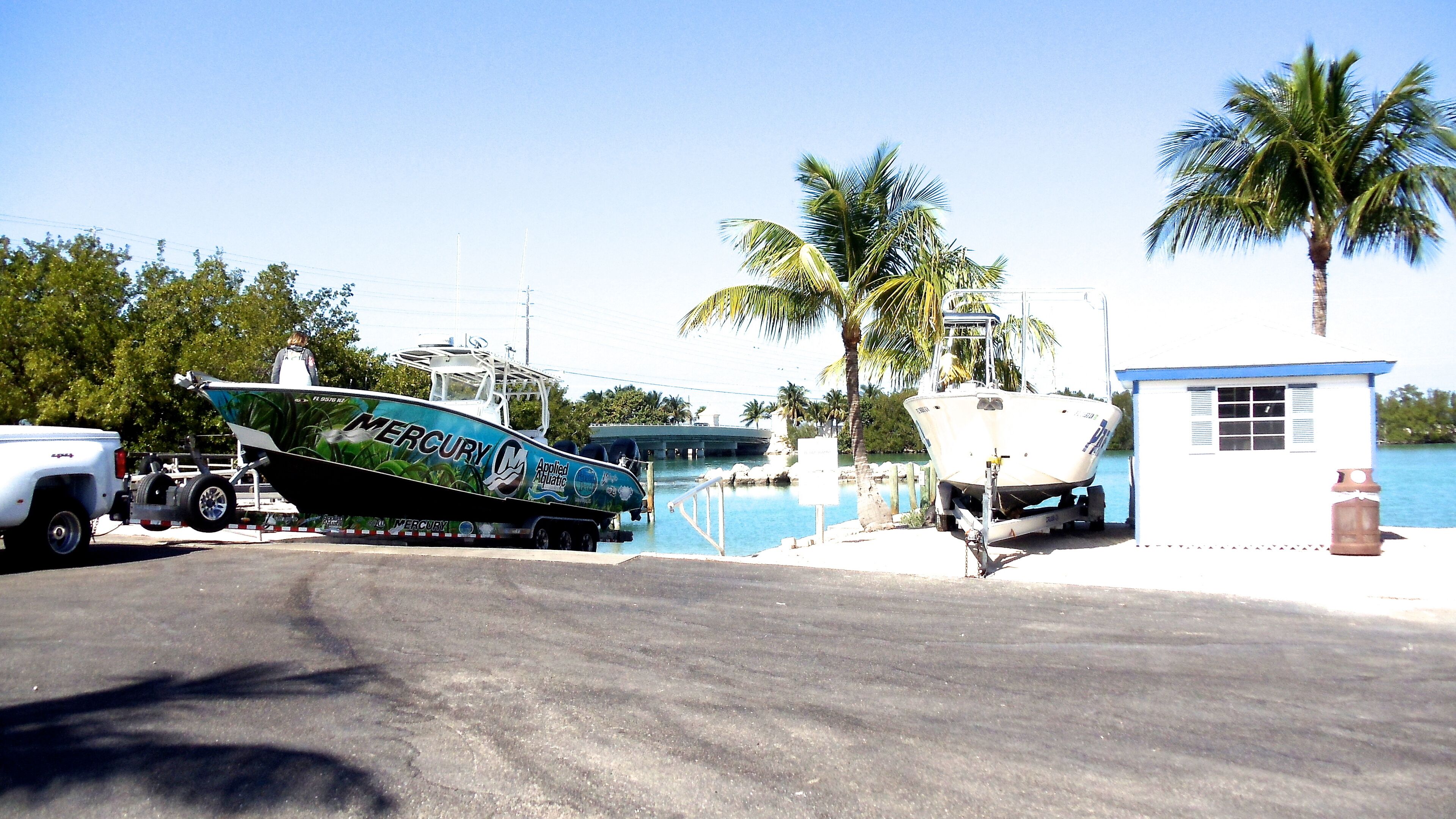 A boat named 'Mercury' docked at a marina with a small white building nearby.