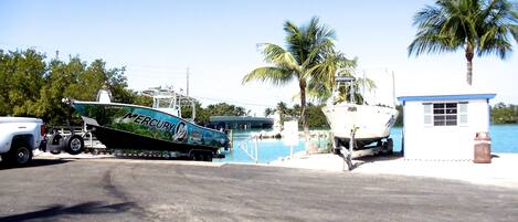 A boat named 'Mercury' docked at a marina with a small white building nearby.