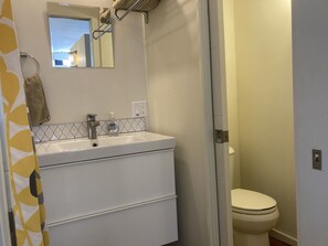 Een bad/douchecombinatie, een haardroger, handdoeken, zeep