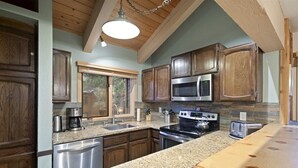 Una cocina con armarios de madera, encimeras de granito, electrodomésticos de acero inoxidable y una mesa de comedor de madera.