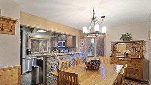 Una cocina con una isla de piedra, armarios de madera y un comedor con una mesa grande y sillas.