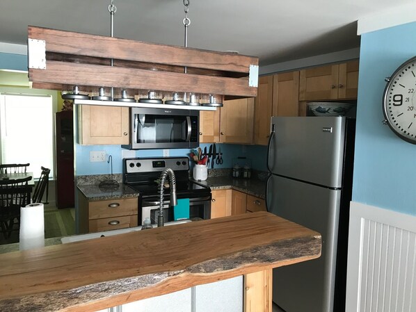 A kitchen with wooden cabinets, a stainless steel refrigerator, a microwave, and a sink with a faucet.