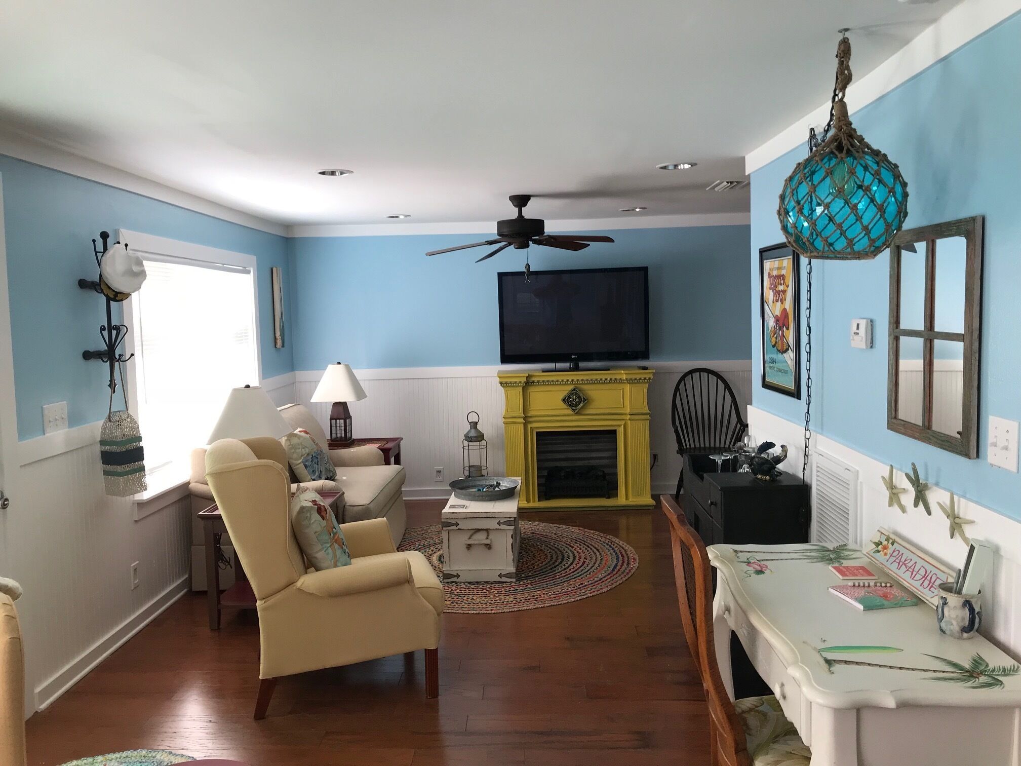 A living room with a beige armchair, a yellow fireplace, a television, and a blue wall.