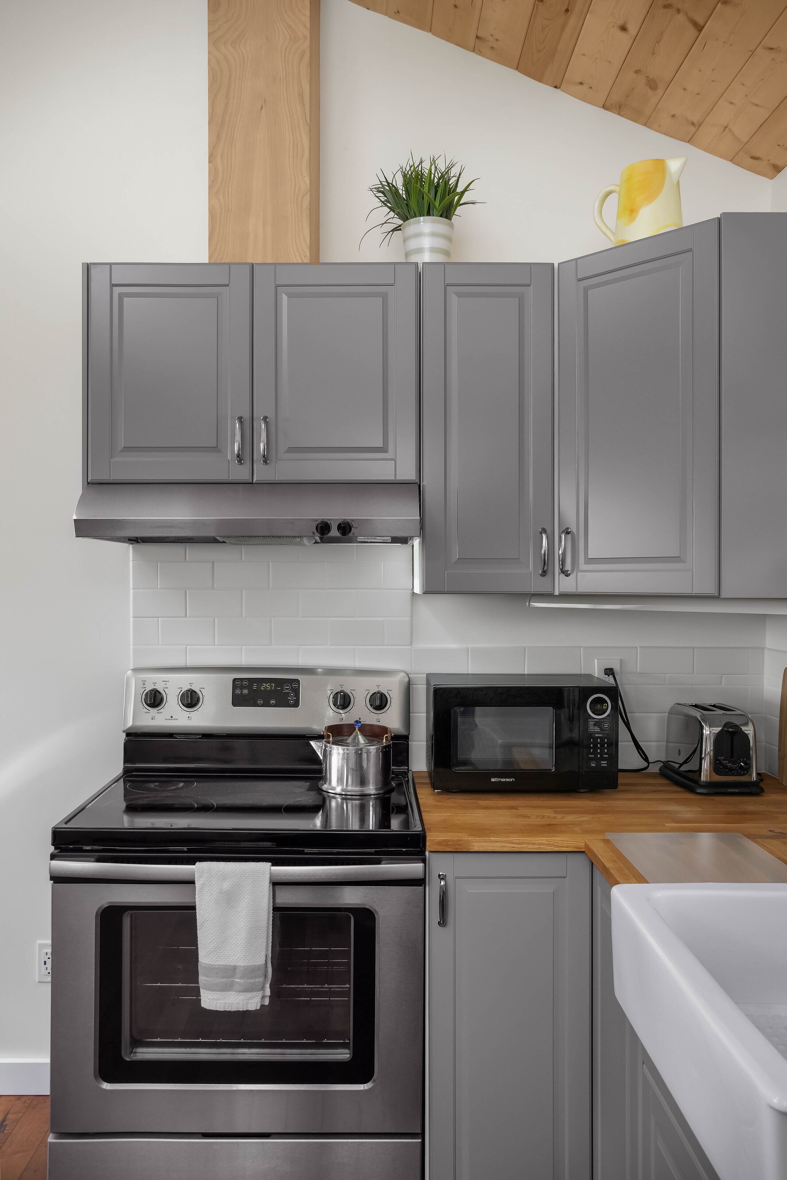 A kitchen with grey cabinets, a stainless steel oven, a microwave, and a toaster.