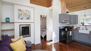 A modern kitchen with grey cabinets, a stainless steel stove, and a microwave. There is a dining area with a wooden table and chairs. - Charming Fireplace! Walk to Alberta Arts SilverStar cottage in NE Portland. (Portland)