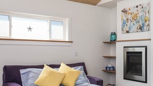 A modern bedroom with a loft bed, a window with star decoration, a fireplace, and a colorful abstract painting. - Charming Fireplace! Walk to Alberta Arts SilverStar cottage in NE Portland. (Portland)