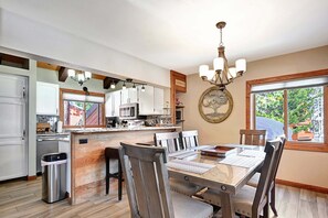 A modern kitchen with white cabinets, a central island, and a dining area with a large table and chairs.