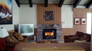 A living room with a fireplace, two sofas, a TV, and a painting on the wall. - Chamonix 60: Walk To The Lifts (Mammoth Lakes)
