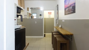 Un pasillo con una zona de cocina, un letrero de 'No fumar', un cartel de 'Bienvenido a Nueva York' y un banco.