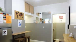 Una cocina moderna con paredes grises, armarios de madera y una mesa de madera. Hay letreros en la pared, incluyendo un letrero de 'No Fumar' y un letrero que indica 'Silencio, gente durmiendo'.