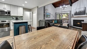 Eine moderne Küche mit Edelstahlgeräten, ein Essbereich mit Holztisch und ein gemütlicher Wohnbereich mit Kamin.