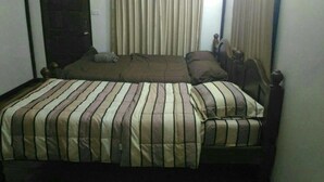 A double bed with striped bedding, a wooden headboard, and a window with vertical blinds. - Rai Monsicha Khaokho (Khao Kho)