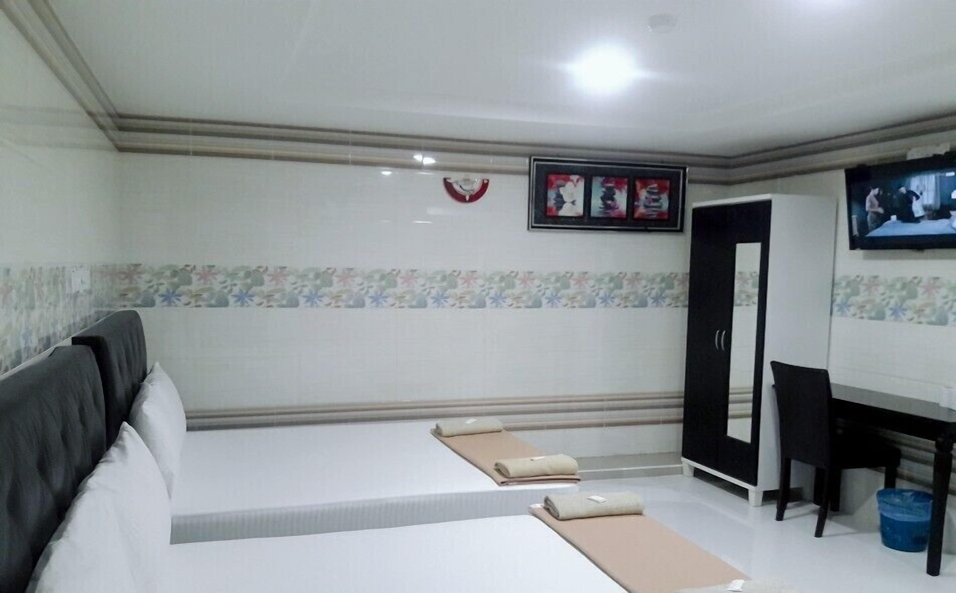 Una habitación de hotel con cama, escritorio, televisor y puerta.