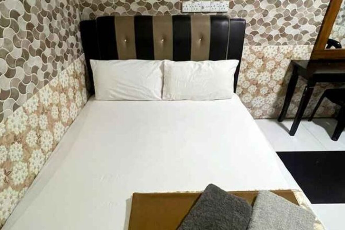 A bed with a striped headboard, white pillows, and a box with pillows on the bed.