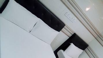 A hotel room with a bed, a bedside table, and a wall-mounted power outlet.