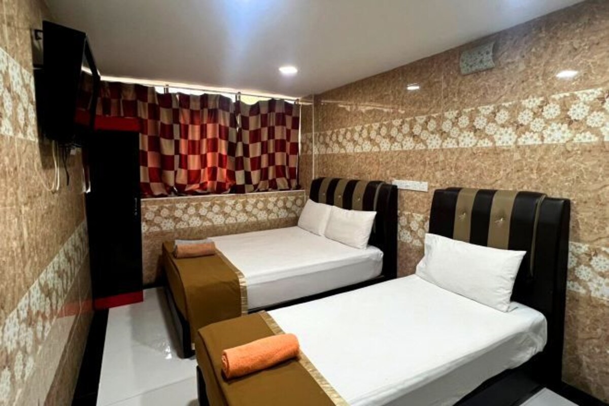 A hotel room with two beds, a television, and a patterned wall.
