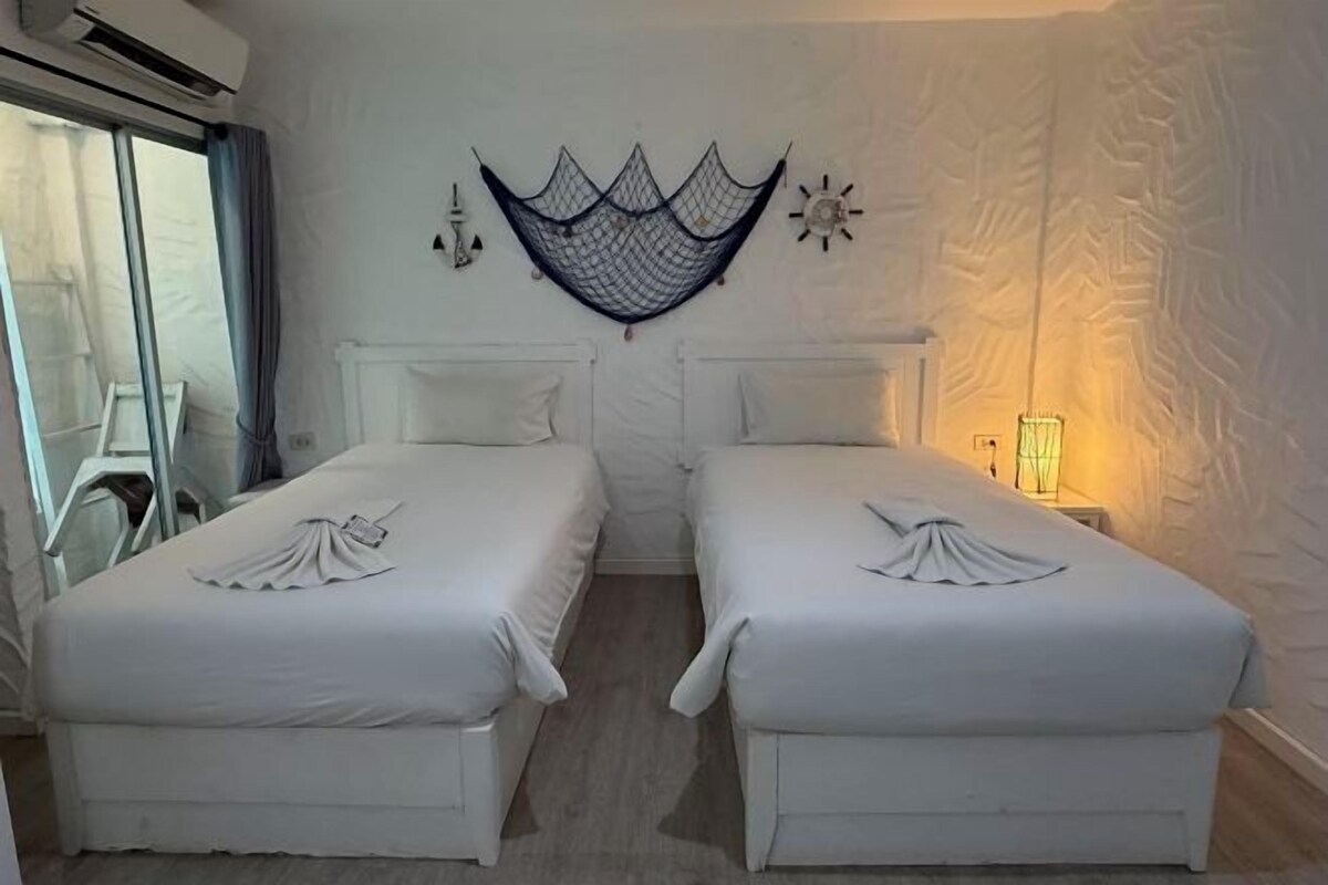 A room with two beds, a hammock, and a wall-mounted decorative piece.