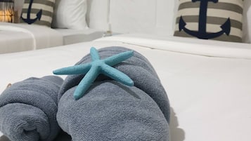 A neatly made bed with a starfish decoration, striped pillows, and a nautical-themed wall hanging.