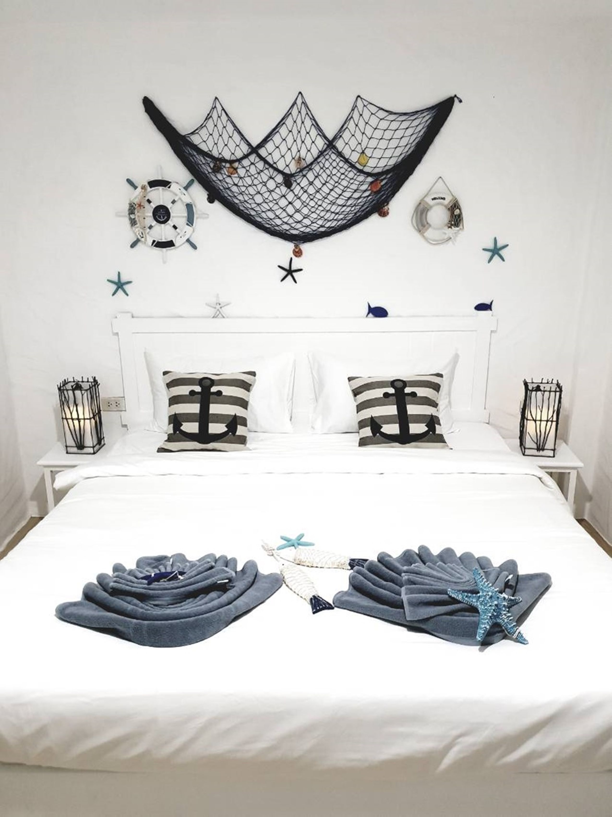 A neatly made bed with striped pillows, a hammock, and starfish decorations on the wall.
