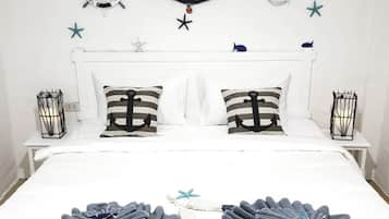A neatly made bed with striped pillows, a hammock, and starfish decorations on the wall.