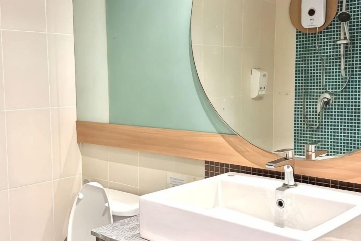 Un baño con un lavamanos blanco, un inodoro y un espejo.