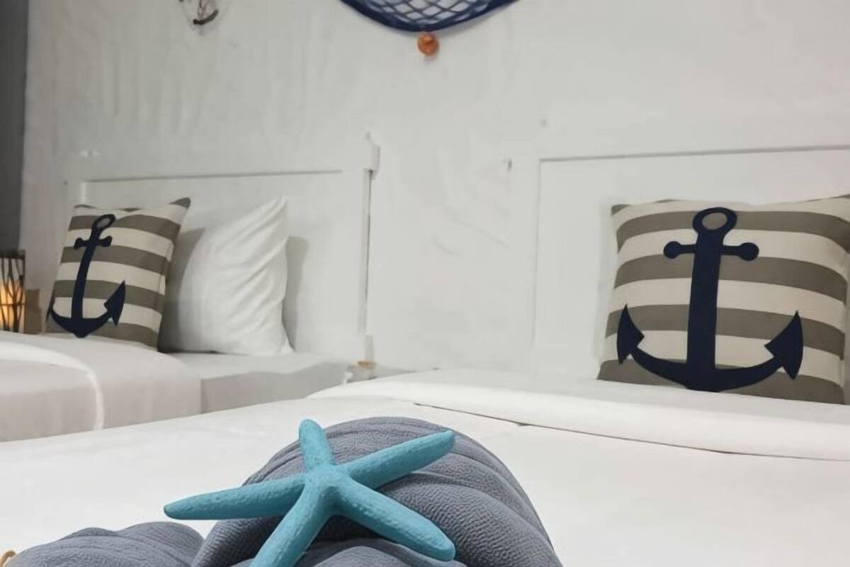 Ein Schlafzimmer mit einem Bett, Kissen mit Anker-Motiven und einer Meerstern-Dekoration.