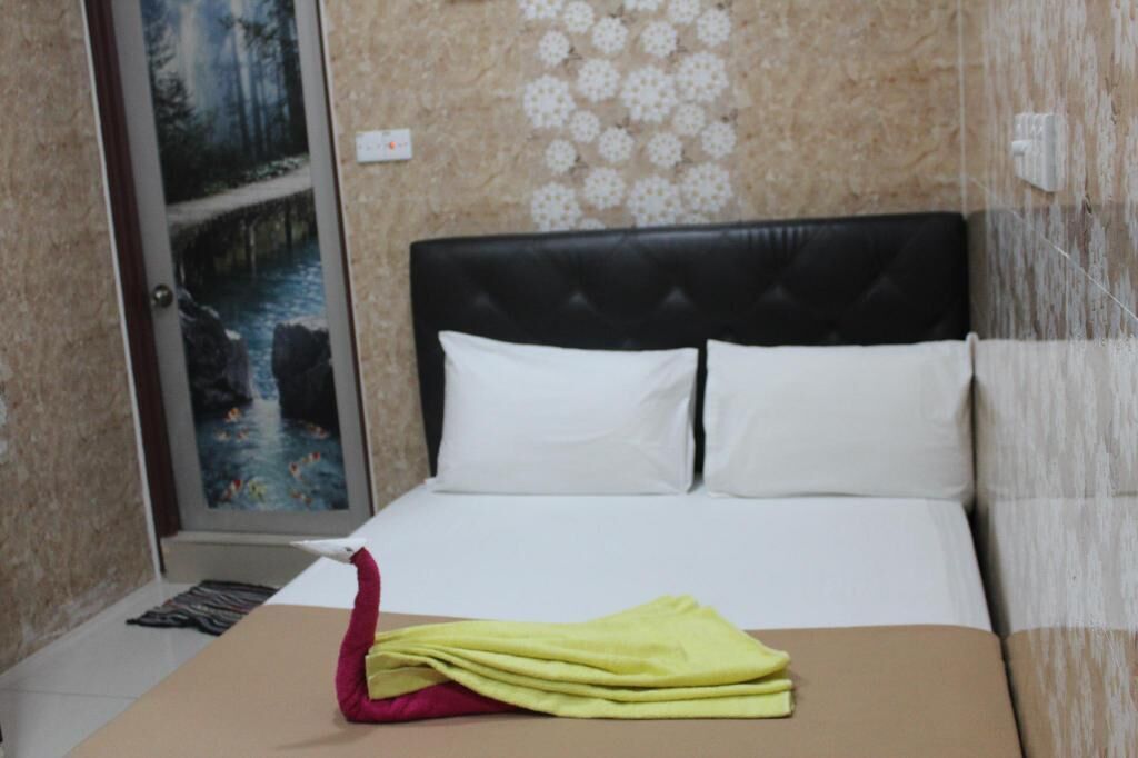 A hotel room with a bed, a painting on the wall, and a patterned wall design.