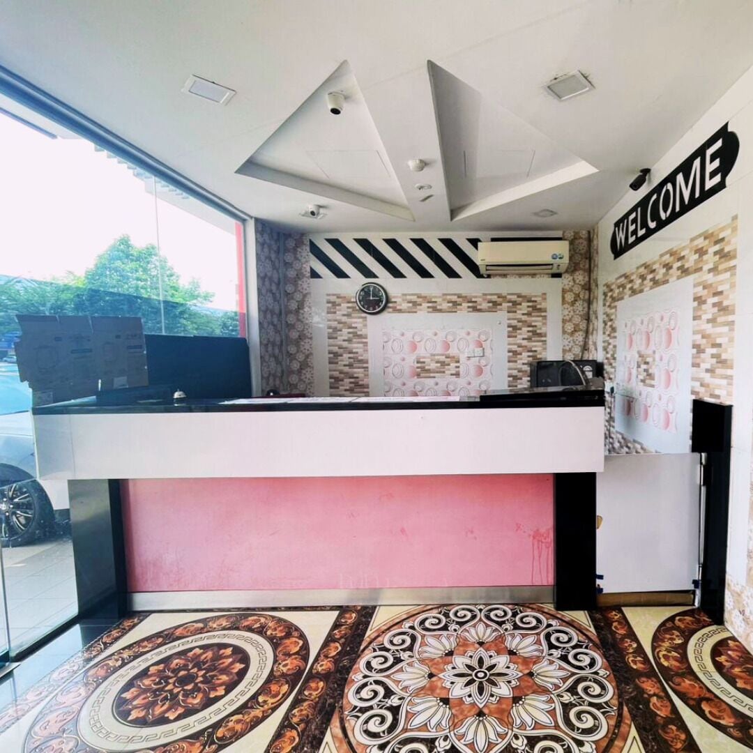 Un espace d’accueil avec une pancarte « BIENVENUE », une horloge et un revêtement de sol à motifs.