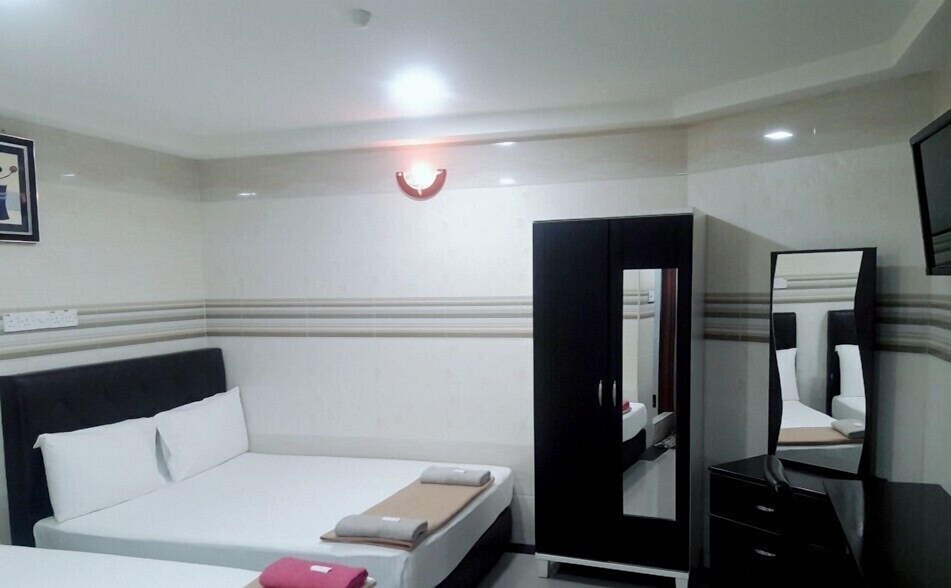 A hotel room with a bed, a wardrobe, a mirror, and a television.