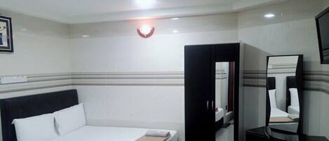 A hotel room with a bed, a wardrobe, a mirror, and a television.