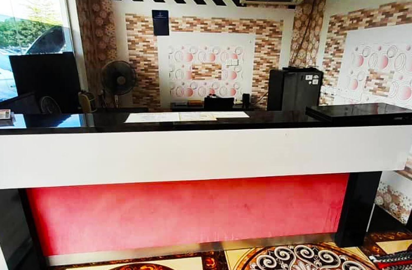 Una mesa de recepción con encimera blanca, sección inferior roja y decoración mural estampada.