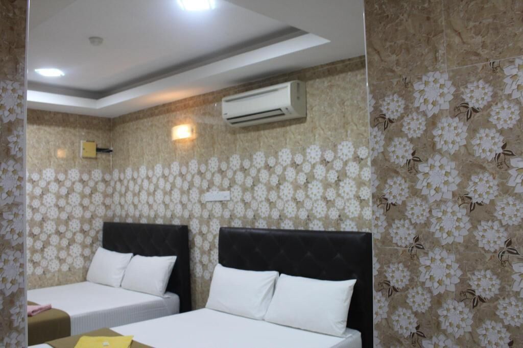 A hotel room with two beds, floral wallpaper, an air conditioning unit, and a ceiling light.