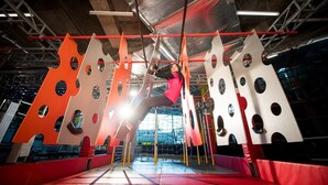 Un área de escalada en interior con paredes acolchadas y suelo cubierto por una red.