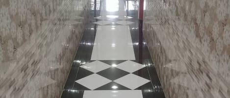 Corredor com paredes estampadas e chão de azulejos com padrão geométrico.