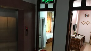 An elevator, a hallway with a bed and curtains, and a dining area with chairs and a table.